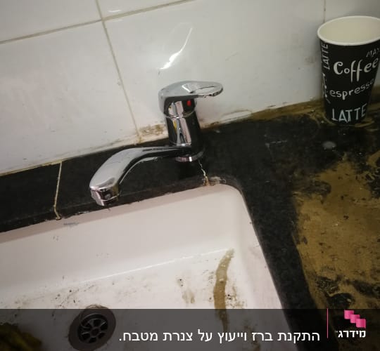ברז מטבח עם כיור מלוכלך ומטלית צהובה